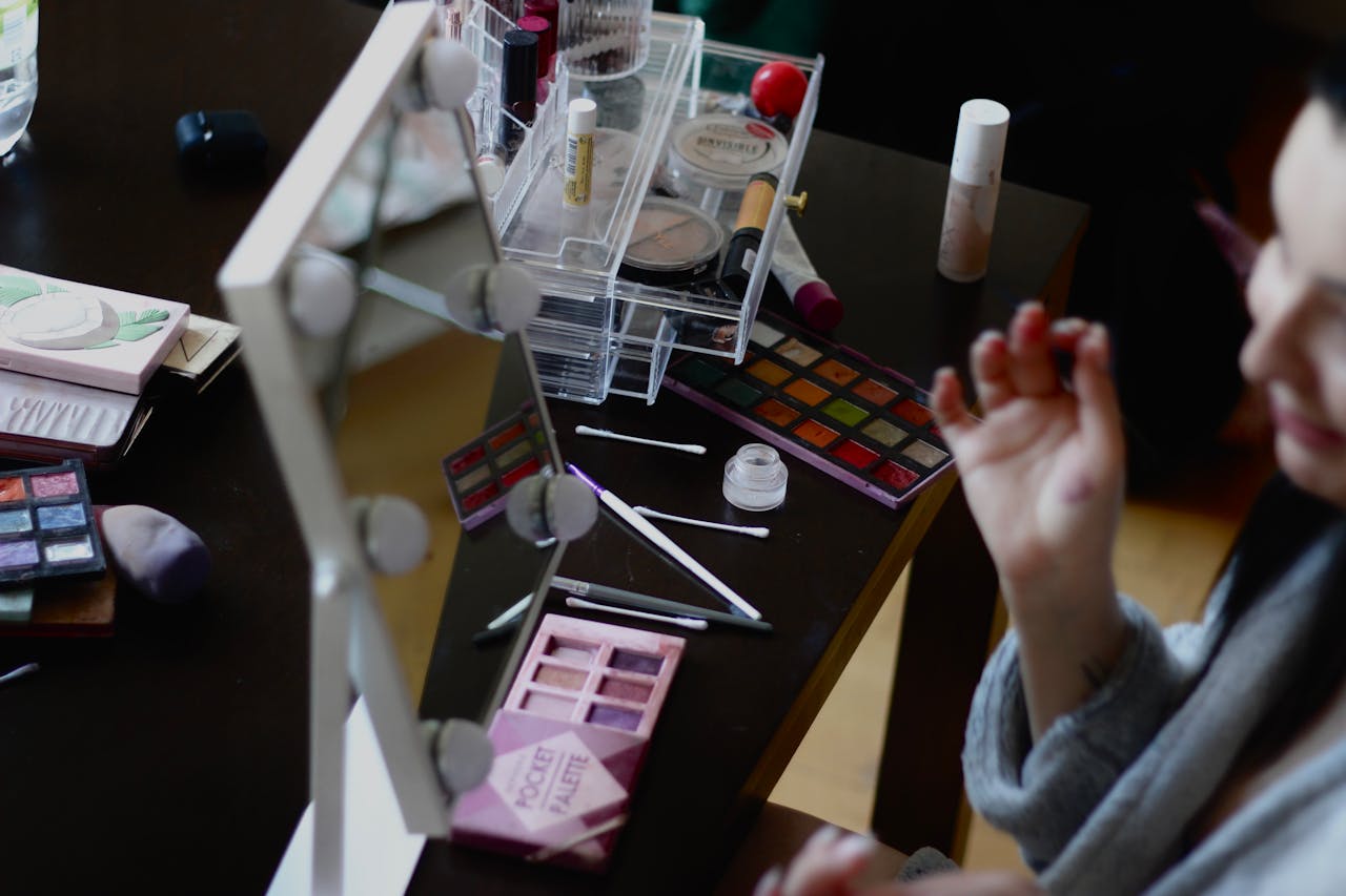 hero-img-02 A makeup setup with various cosmetics and mirror reflection captured indoors.
